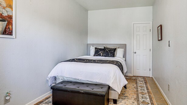 A bedroom with a bed, a bench, a door, and a painting on the wall. - Triple-unit Galt Escape Near Lodi Vineyards! (Galt)