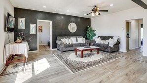 A living room with a dark accent wall, a ceiling fan, a coffee table, and a sofa. - Triple-unit Galt Escape Near Lodi Vineyards! (Galt)