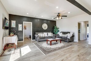 Ein Wohnzimmer mit dunkler Akzentwand, Deckenventilator, Couchtisch und Sofa.