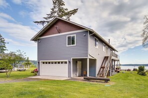 A two-story house with a covered porch and a garage. - South-facing Herron Island Retreat w/ Sound Views! (Lakebay)