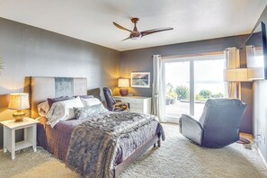 A bedroom with a bed, a desk, a chair, a ceiling fan, and a view through a glass door. - South-facing Herron Island Retreat w/ Sound Views! (Lakebay)