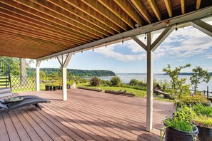 Una terraza de madera con pérgola, mobiliario exterior y plantas en macetas.