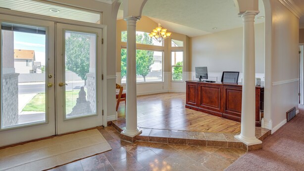 A spacious interior with a large open area, a wooden reception desk, and a view through a glass door. - Office, Fire Pit, Deck! Large Rental Near Hill AFB (Clearfield)