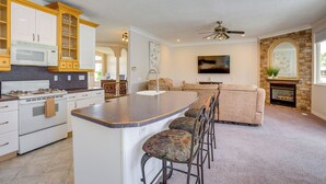 A kitchen with a central island, bar stools, a microwave, and a stove. - Office, Fire Pit, Deck! Large Rental Near Hill AFB (Clearfield)