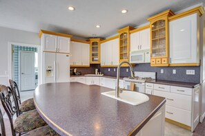 A kitchen with white cabinets, a granite countertop, a sink, and a dining area with chairs. - Office, Fire Pit, Deck! Large Rental Near Hill AFB (Clearfield)