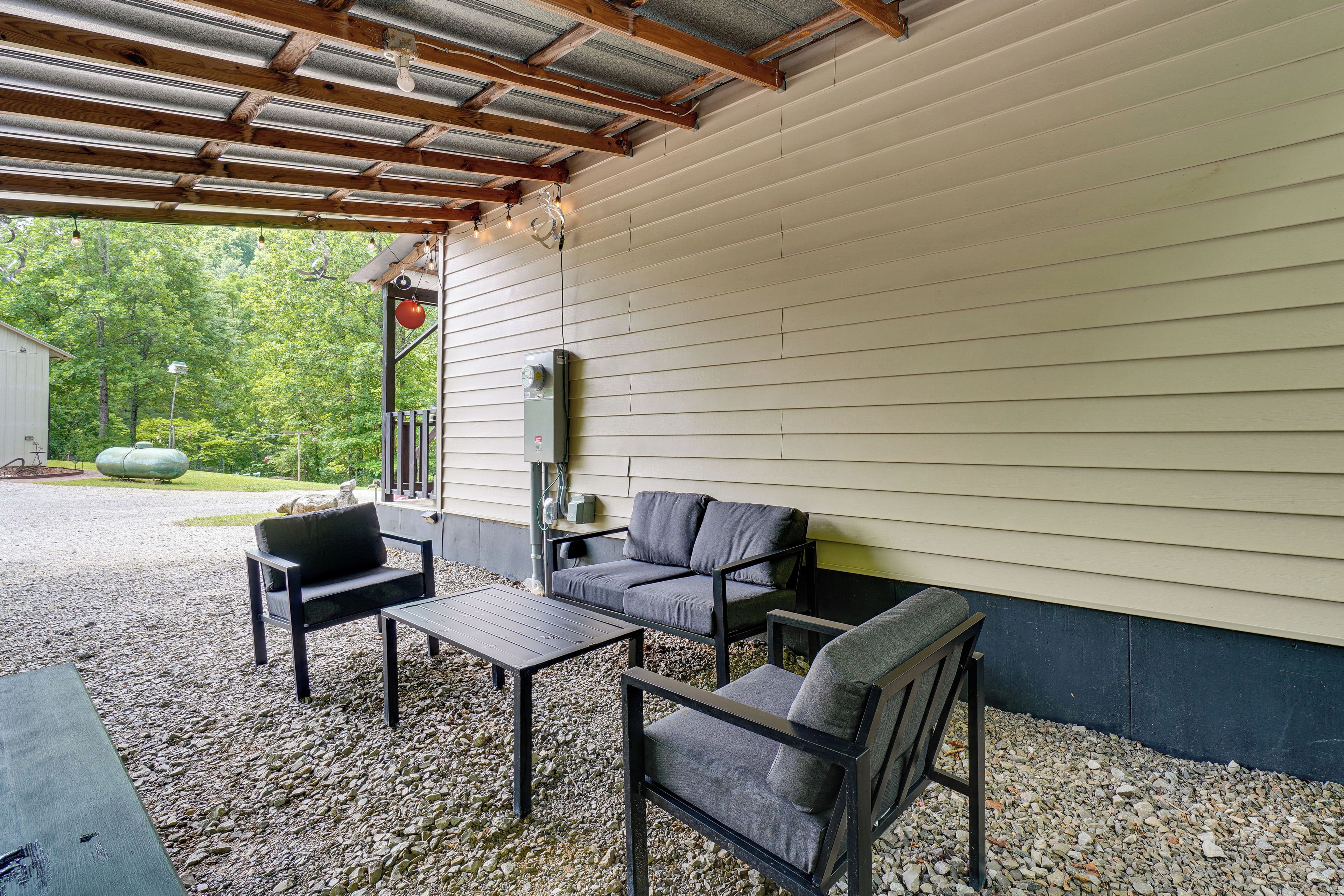 An outdoor patio area with a covered seating arrangement, a table, and a stone-paved ground.