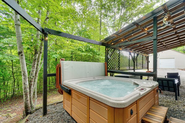 A hot tub in a wooded area with a pergola overhead. - Smoky Mtn Tiny Cabin Hideaway: Hot Tub, Patio (Englewood)