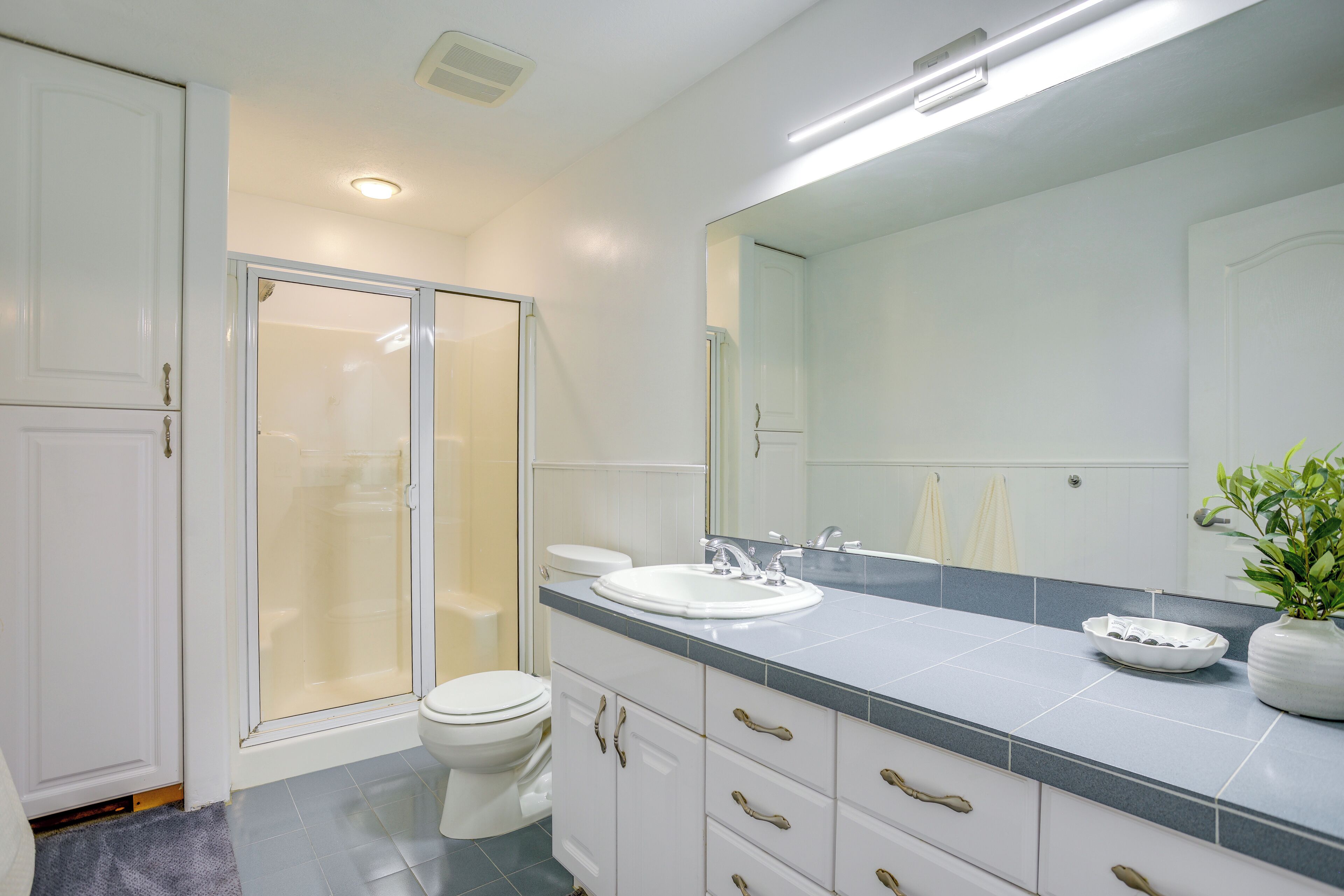 Une salle de bain moderne équipée d’une douche, de toilettes, d’un lavabo et d’un grand miroir.