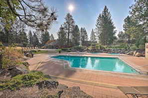 A swimming pool with a tiled deck, surrounded by rocks and trees. - Resort Pool & Trails! Cozy Seventh Mountain Condo (Bend)