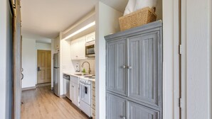 A kitchen with white cabinets, a wooden floor, and a basket on top of a cabinet. - Resort Pool & Trails! Cozy Seventh Mountain Condo (Bend)