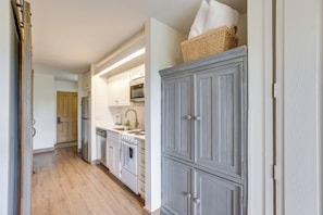A kitchen with white cabinets, a wooden floor, and a basket on top of a cabinet. - Resort Pool & Trails! Cozy Seventh Mountain Condo (Bend)