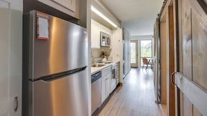 A kitchen with stainless steel appliances, wooden cabinets, and a view to a balcony. - Resort Pool & Trails! Cozy Seventh Mountain Condo (Bend)