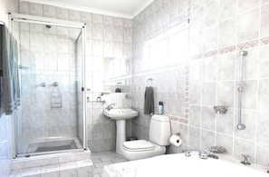 A bathroom with a glass-enclosed shower, a sink, a toilet, and a bathtub.
