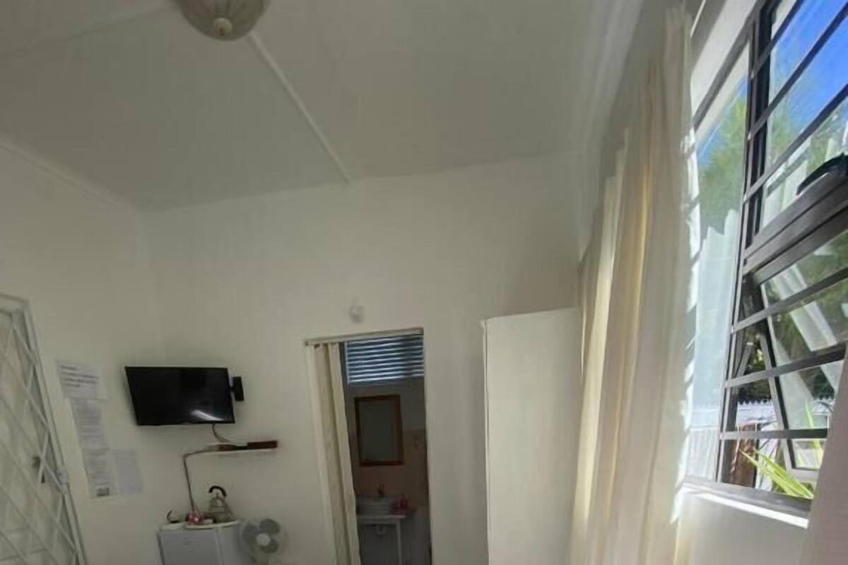 Un dormitorio con cama, mesita de noche y televisor montado en la pared.