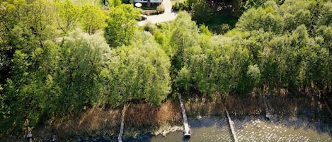 Vista aérea de una propiedad junto al lago con una casa, barcos y abundante vegetación.