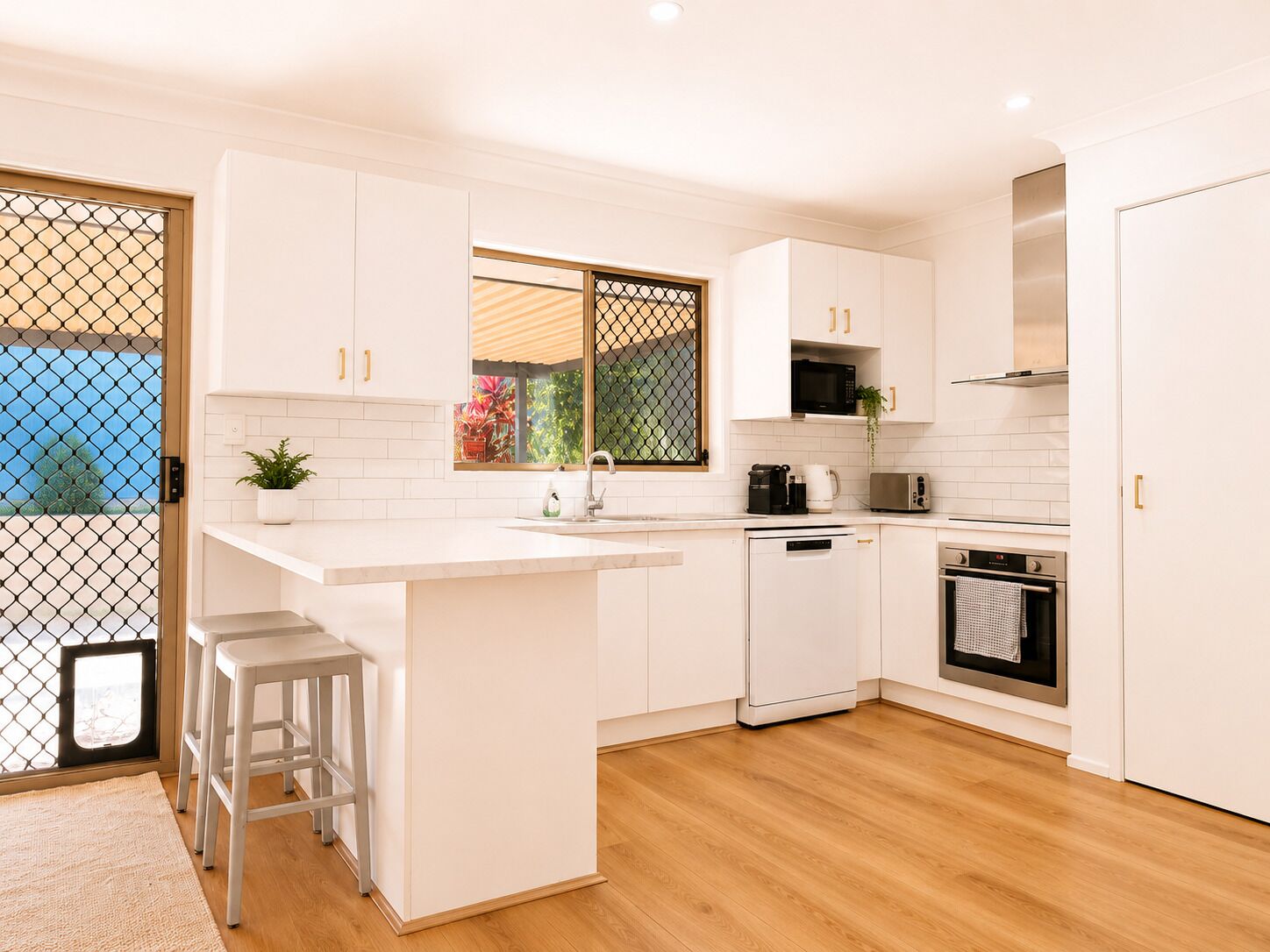 A modern kitchen with white cabinetry, a central island, a microwave, a coffee maker, and an oven.