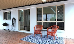 Un patio con dos sillas rojas, una mesa y un tapete estampado.