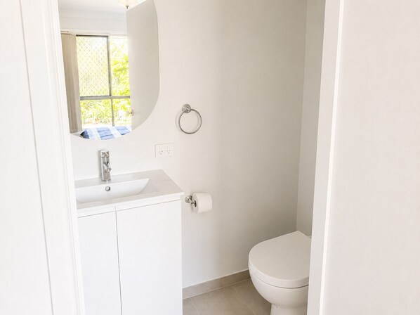 A small, white bathroom with a toilet, a sink, and a mirror.