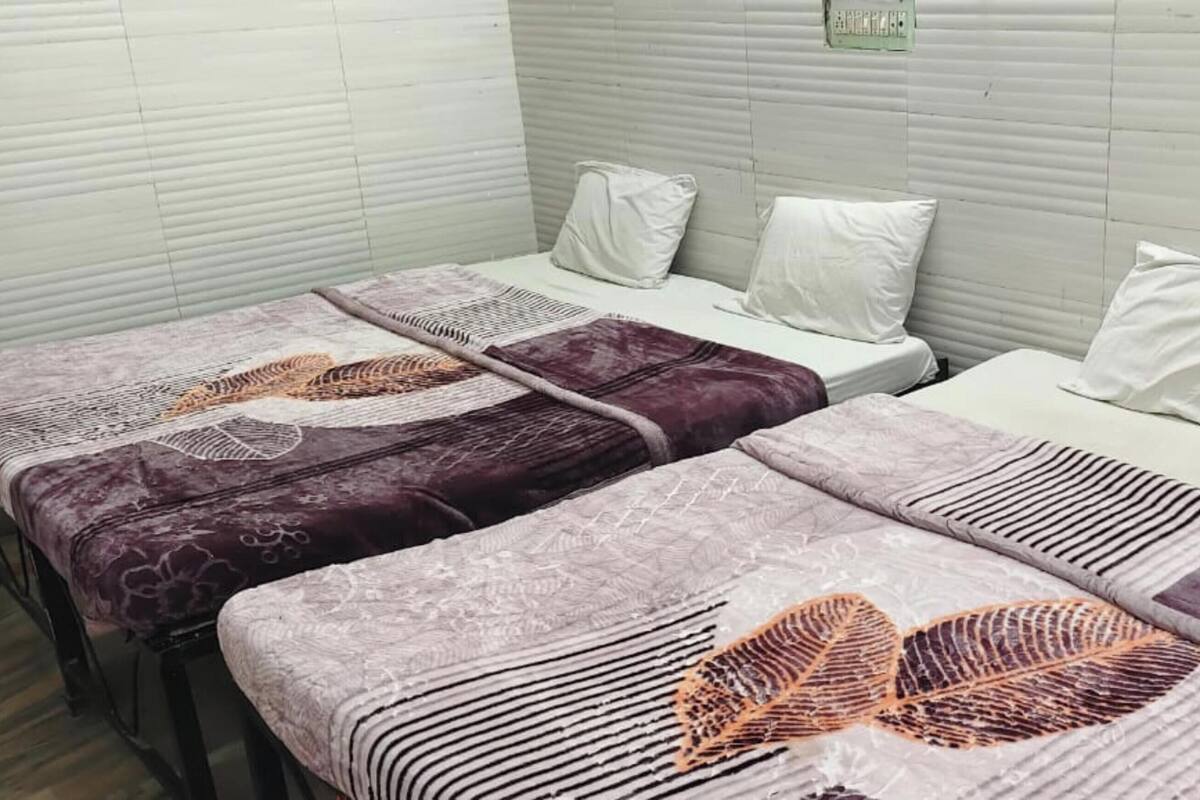 Una habitación de hotel con dos camas, cada una con una colcha estampada y almohadas blancas.