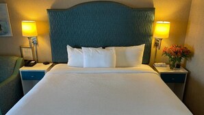Habitación de hotel con una cama grande, dos mesitas de noche, un cabecero y dos lámparas.