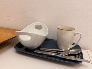 A tray with a white mug, a white cup, and cutlery on a table.