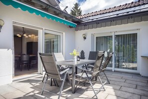 An outdoor patio with a table and chairs, a satellite dish, and a sliding glass door. - Central Apartment with Pool, Private Terrace, and Wi-Fi (Oberstaufen)