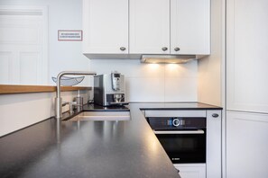 A modern kitchen with white cabinets, a Bosch dishwasher, a coffee machine, and a stainless steel sink. - Central Apartment with Pool, Private Terrace, and Wi-Fi (Oberstaufen)