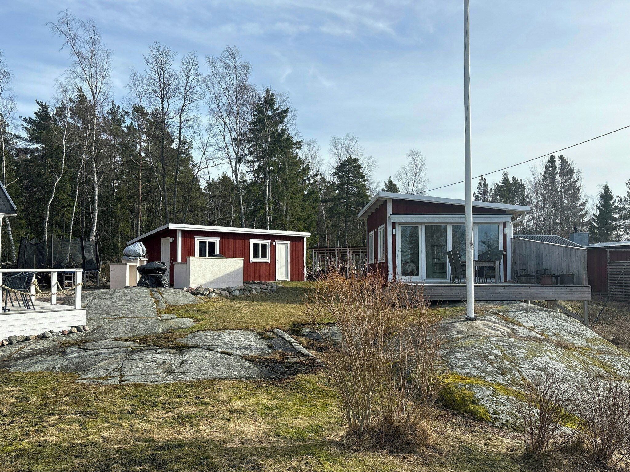 Une cabane avec un petit porche, une terrasse et une grande fenêtre.