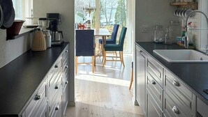Een keuken met houten kastjes, een eetgedeelte met stoelen en een uitzicht door het raam.