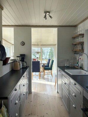 Eine Küche mit Holzausstattung, ein Essbereich mit Stühlen und ein Blick durch das Fenster.