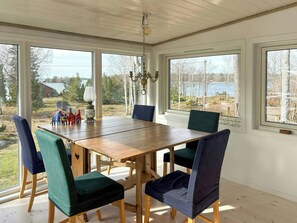 Ein Essbereich mit Holztisch und Stühlen, großen Fenstern mit Blick auf Bäume und einen See, sowie einer Kristallleuchtre.'