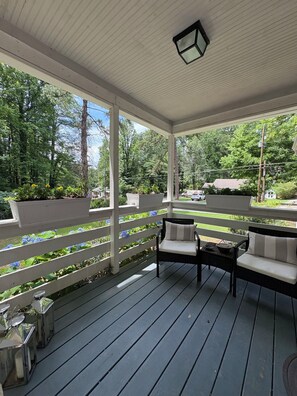 A covered porch with a bench and table, surrounded by a white fence and greenery. - Charming 3BR Atlanta Bungalow • Minutes to Midtown & Mercedes‑Benz Stadium (Atlanta)