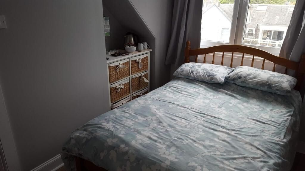 Ein Schlafzimmer mit Bett, Schminktisch und Fenster.