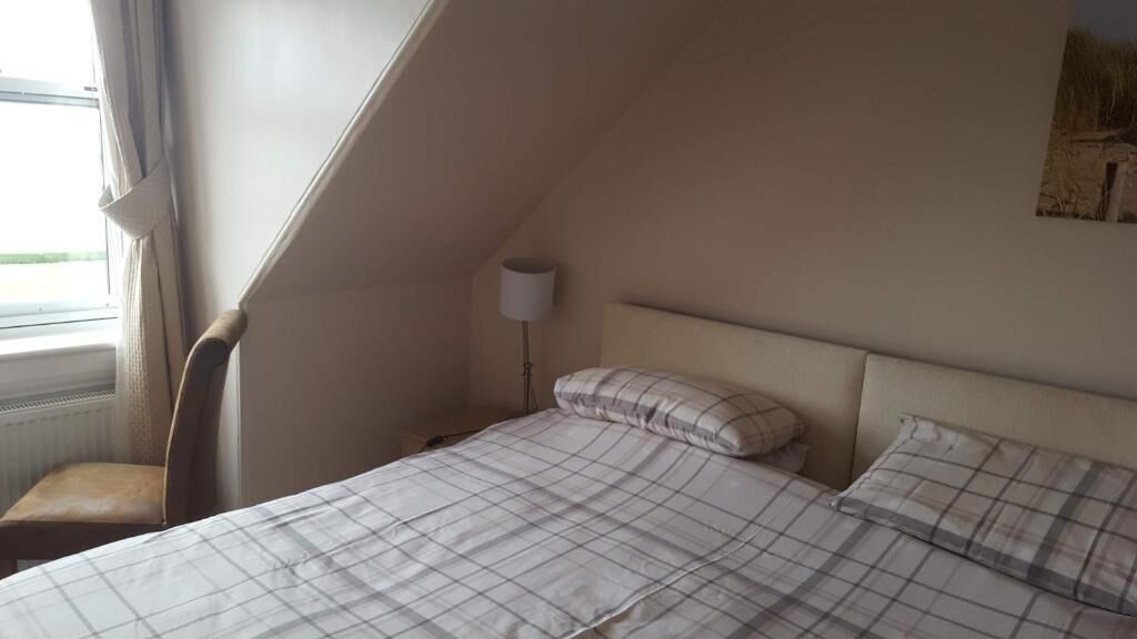 A bedroom with a bed, a chair, a lamp, and a window.
