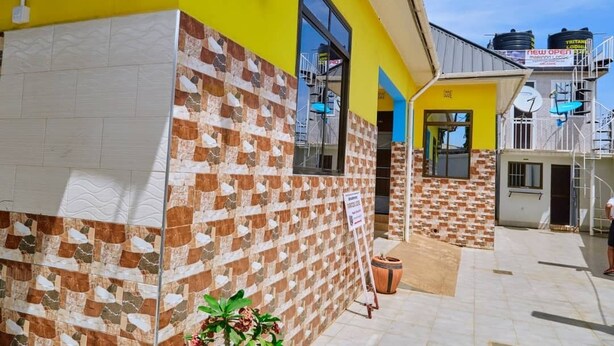 A building with a yellow exterior, a tiled wall pattern, and a visible entrance. - Marindo Lodge Moshi (Moshi)