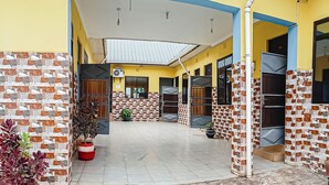 A covered outdoor area with tiled flooring, potted plants, and a brick-patterned wall. - Marindo Lodge Moshi (Moshi)