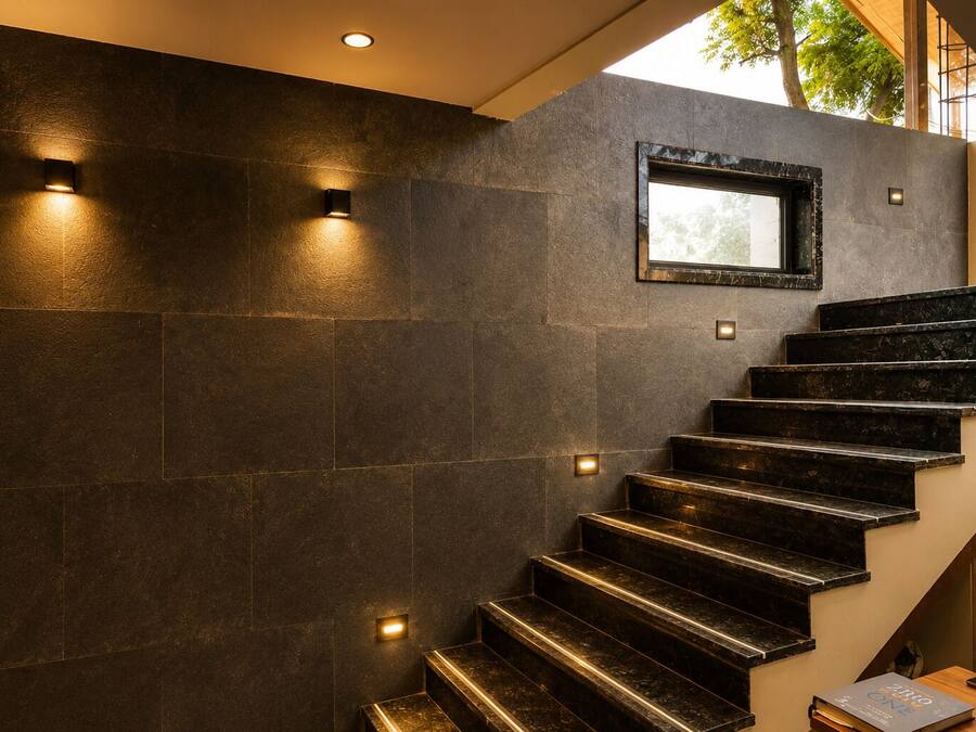 Eine moderne Treppe mit dunklen Fliesen und indirekter Beleuchtung.
