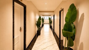 A hotel hallway with a marble floor, potted plants, and doors on either side. - Hotel Casa Brij Boutique Near Nakki Lake, Mount Abu (Mount Abu)