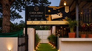 A hotel entrance with a signboard for CASA BRIJ BOUTIQUE, featuring a bed, a tree, and potted plants. - Hotel Casa Brij Boutique Near Nakki Lake, Mount Abu (Mount Abu)