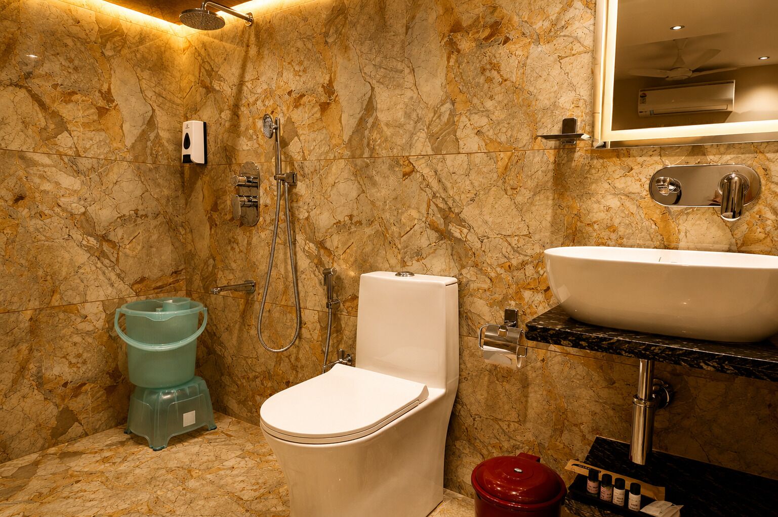 A bathroom with a toilet, bidet, sink, and marble walls.