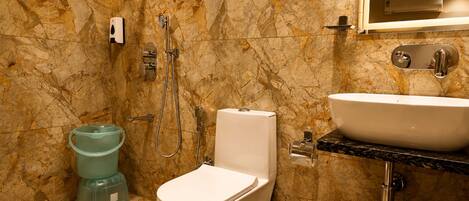 A bathroom with a toilet, bidet, sink, and marble walls.