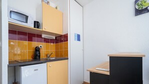 Eine kleine Küche mit Mikrowelle, Kaffeemaschine und Spüle.