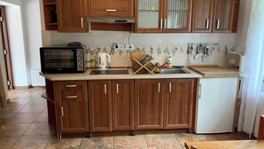 Une cuisine avec des meubles en bois, un four à micro-ondes, une bouilloire et un évier.