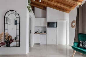 Eine moderne Küche mit weißen Schränken, einem eingebauten Backofen und einem Flachbildfernseher über der Arbeitsfläche.