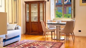 A room with a dining table, chairs, a sofa, a cabinet, and a window with a view of buildings. - Casa Paravia - History Meets Contemporary Comfort (Turin)