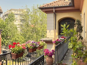 Ein Balkon mit Blumentöpfen, ein Ziegeldach und ein Gebäude mit einem Fenster.