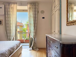 A bedroom with a bed, a dresser, and a balcony with curtains. - Casa Paravia - History Meets Contemporary Comfort (Turin)