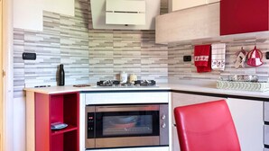 A modern kitchen with a built-in oven, a red chair, and a small shelf unit. - Casa Paravia - History Meets Contemporary Comfort (Turin)
