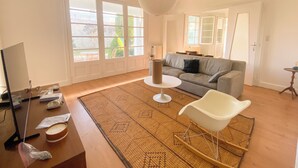 Ein modernes Wohnzimmer mit Sofa, Couchtisch, Fernseher und einem großen Fenster.