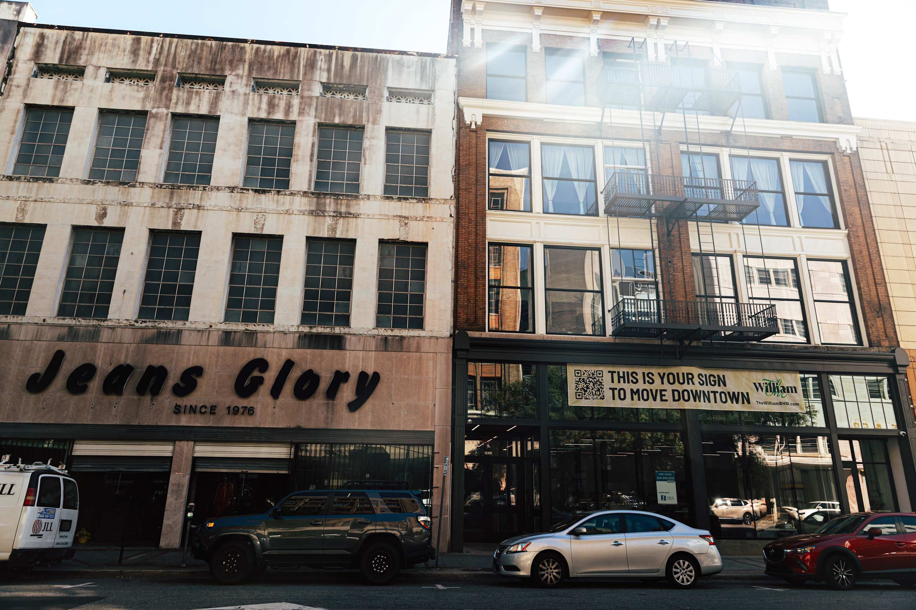 Un edificio con una fachada que muestra el rótulo 'Jeans Glory' y otro anuncio que dice 'Esta es tu señal para mudarte al centro.'